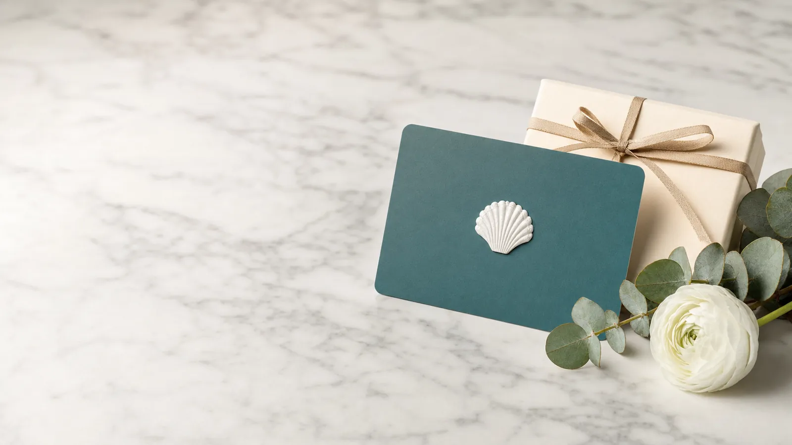 Premium Coastal Maid cleaning services gift card on white marble with a gift box and flowers